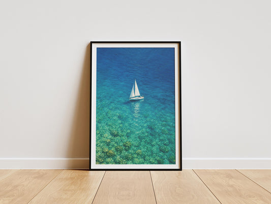 Turquoise ocean wall art print featuring a sailboat floating above crystal-clear water.