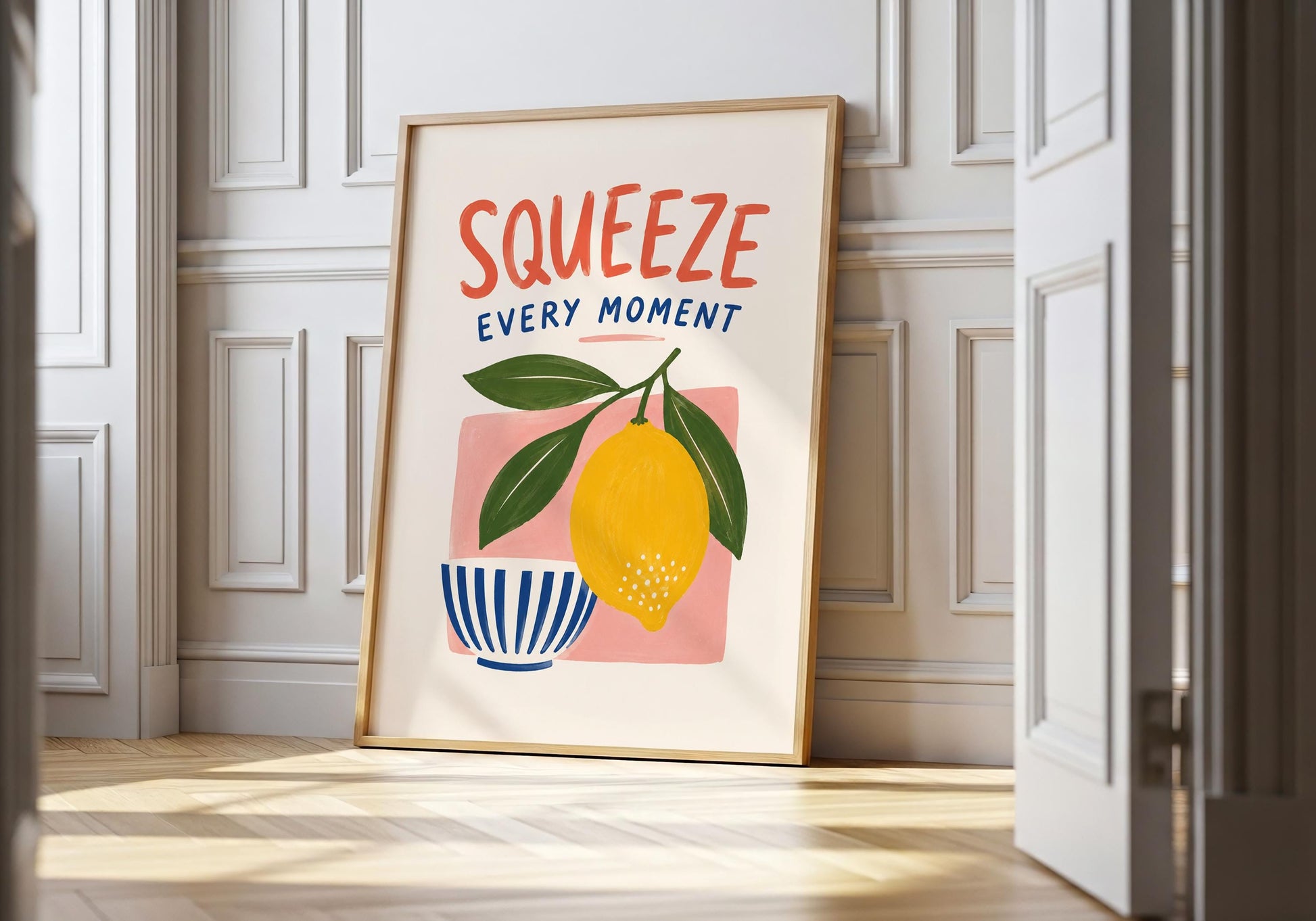 Colourful lemon kitchen wall art with the hand-painted phrase Squeeze Every Moment above a yellow lemon and striped bowl.