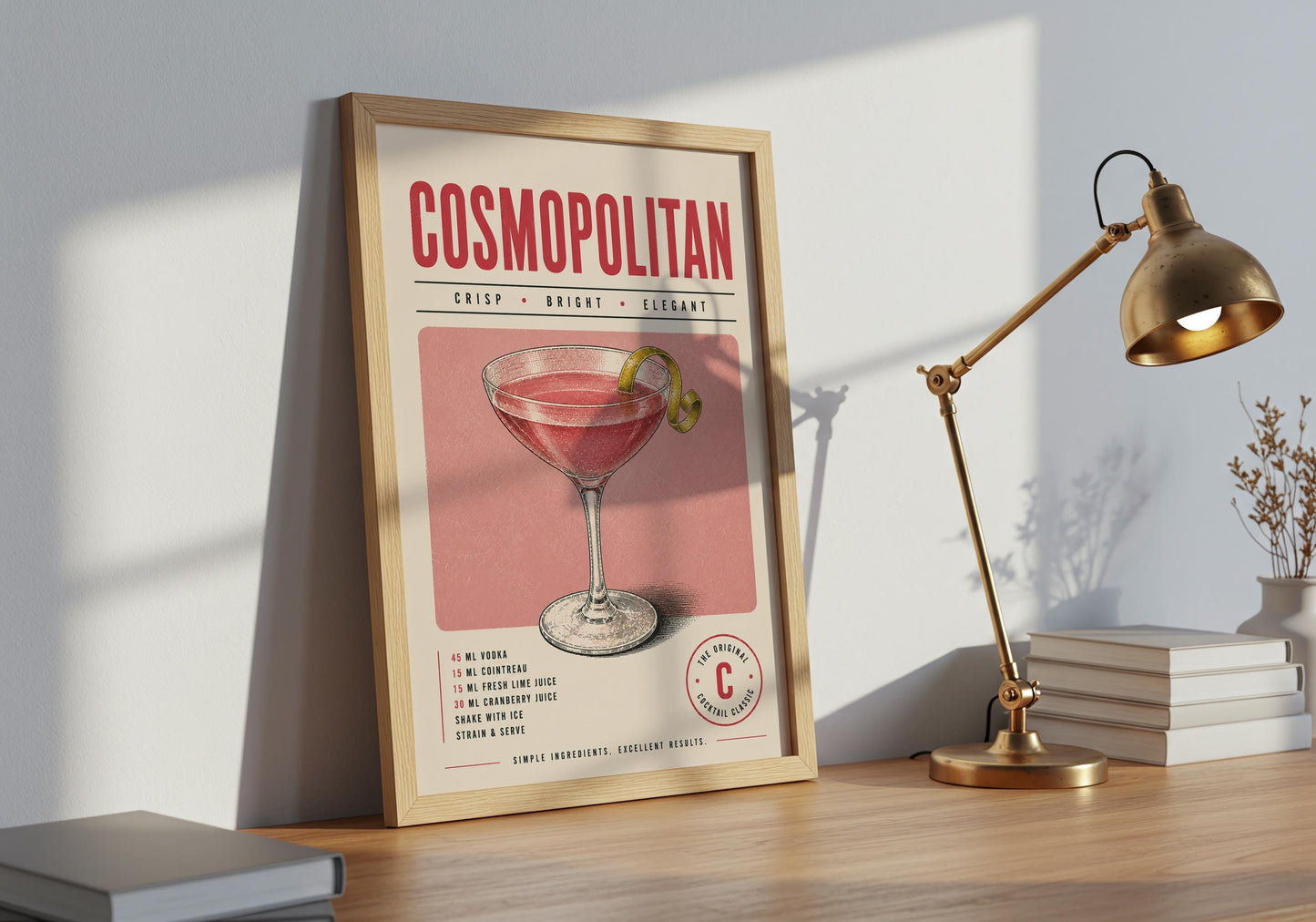Framed Cosmopolitan cocktail print displayed against decorative white wall panelling in a bright interior.