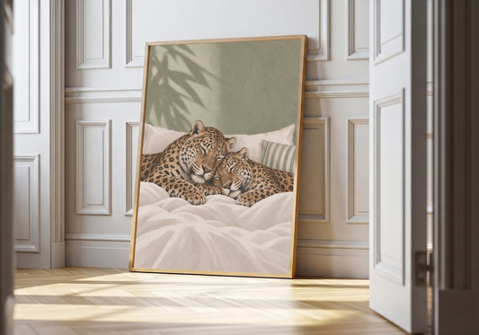 Sleeping Leopards sleeping couple print featuring two spotted leopards snoozing side by side in a soft bed, leaning in a light natural-wood hero frame against bright white panelling.