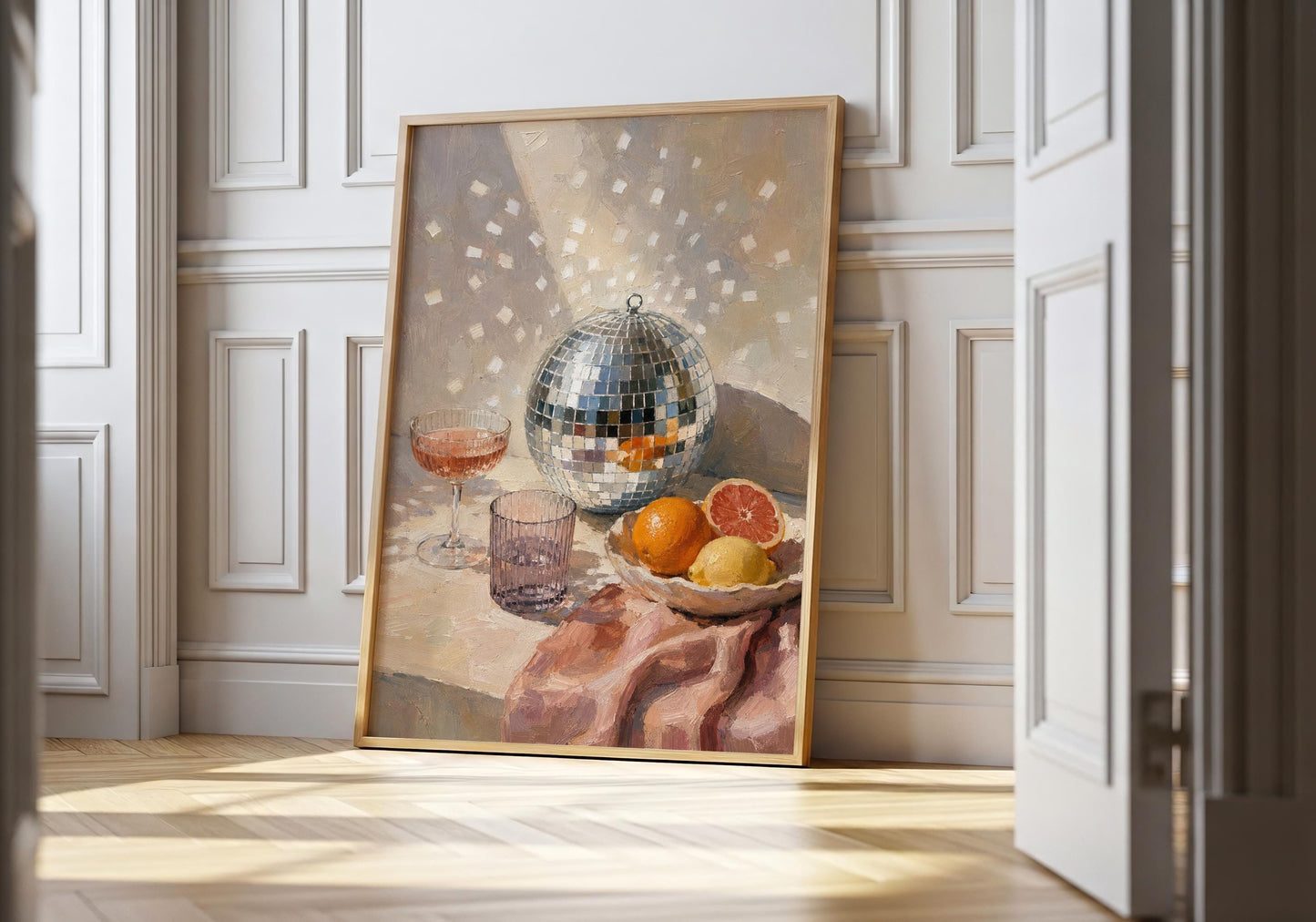 Painterly disco ball wall art featuring a mirrored disco ball, pink cocktail, citrus fruit and ribbed glassware on a table.