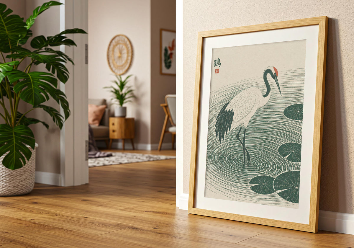 Angled view of water lily art depicting a white crane stepping through deep green ripples and lily pads, shown at an angle in a light wood frame near a doorway.