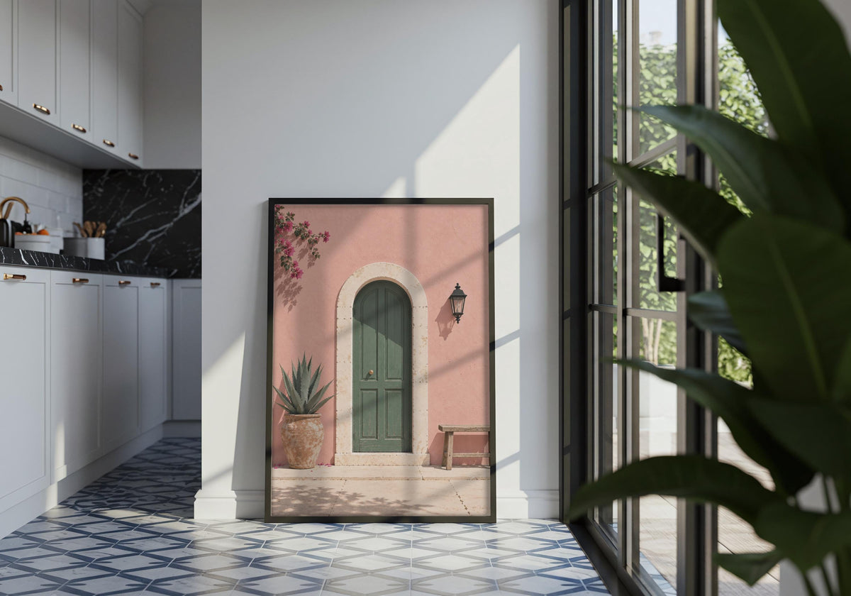 Portrait entryway wall art featuring an arched green door in a blush-pink wall with bougainvillea and a wooden bench, displayed in a black frame in a tiled interior.