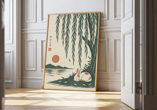 Sleeping bunny art showing a small white rabbit sleeping beside green water beneath long willow leaves, leaning in a light natural-wood hero frame against white panelling.