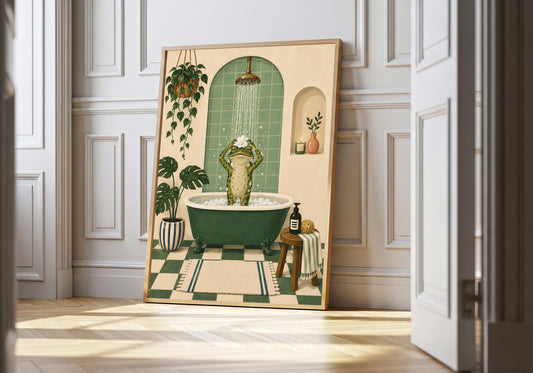 Frog Bath frog bathroom art in a light wood frame, featuring a frog relaxing in a deep green roll-top bath beneath a shower in a plant-filled bathroom.