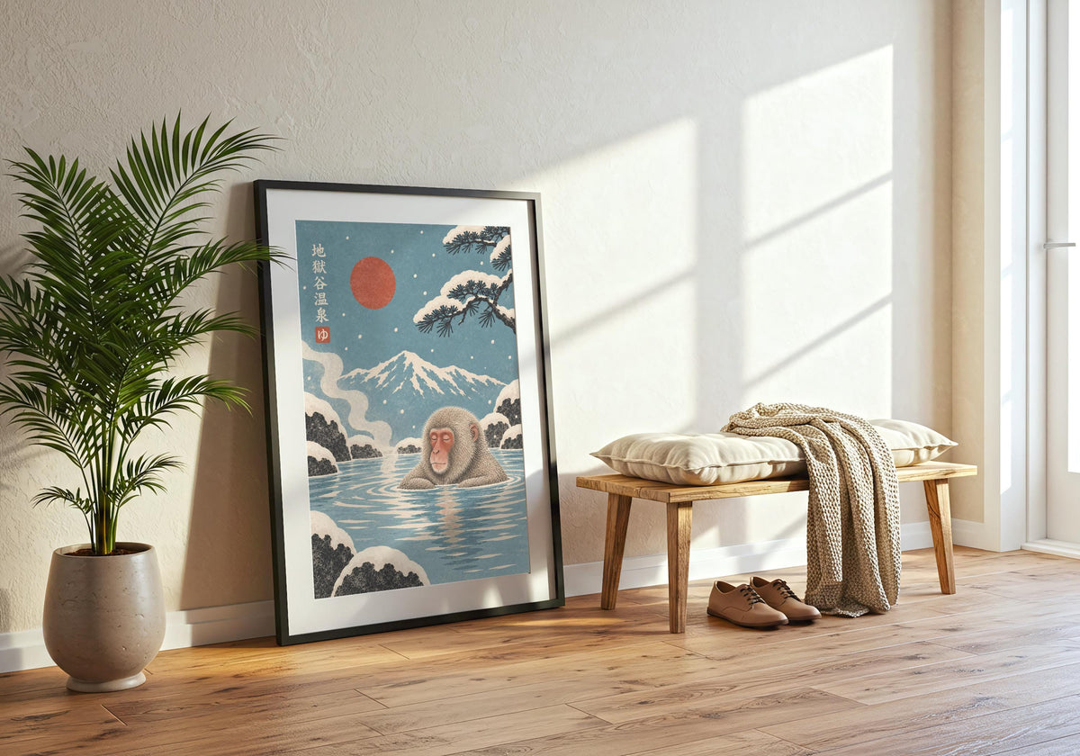 Snow monkeys bathing in a blue hot spring beneath a red sun and snowy mountain forms the focal point of this japanese wall art display in a black frame beside leafy greenery.