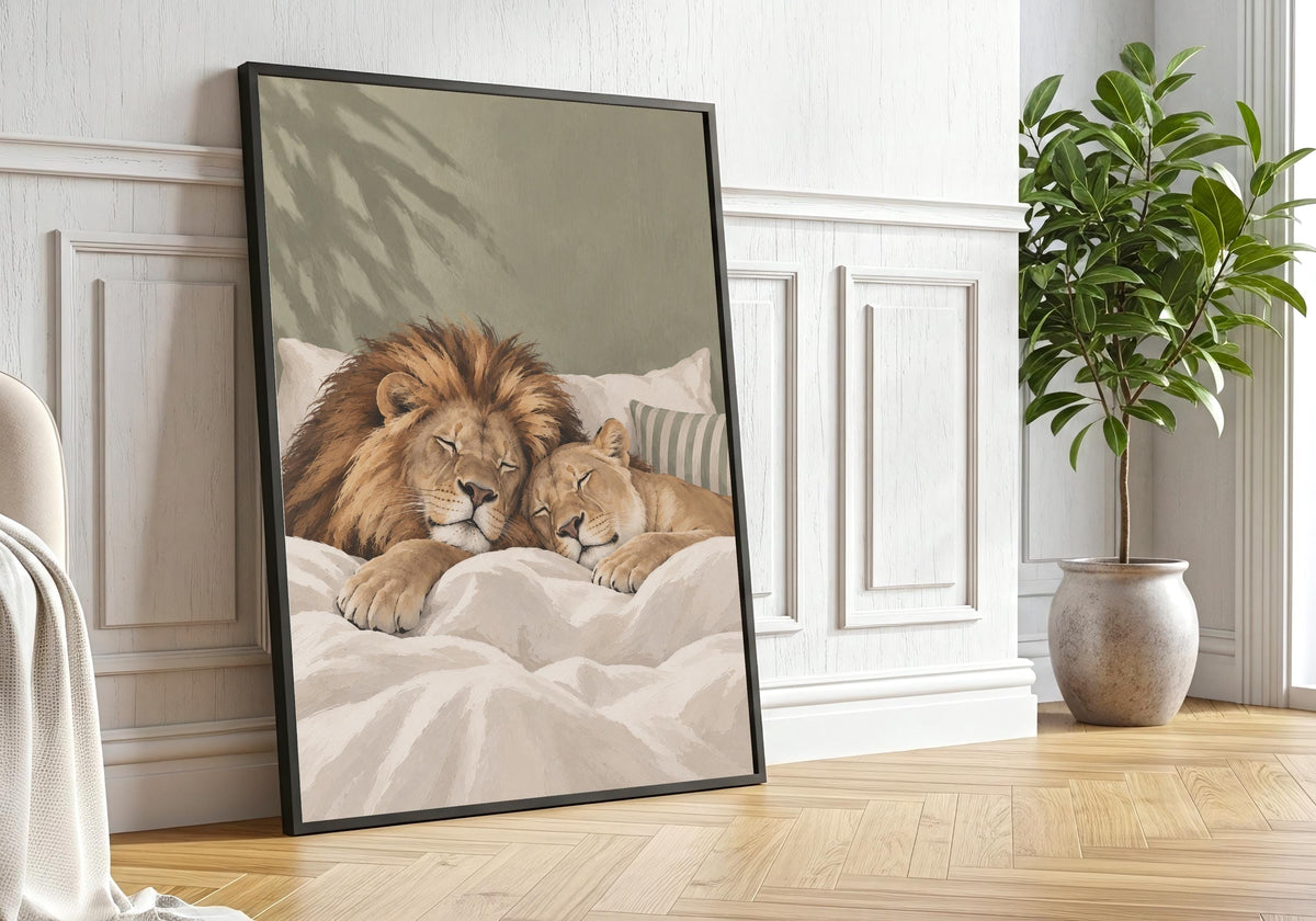 Close styling view of Sleeping Lions, illustrated with a lion and cub enjoying a peaceful bedtime cuddle, hung in a black frame beside leafy green plants.