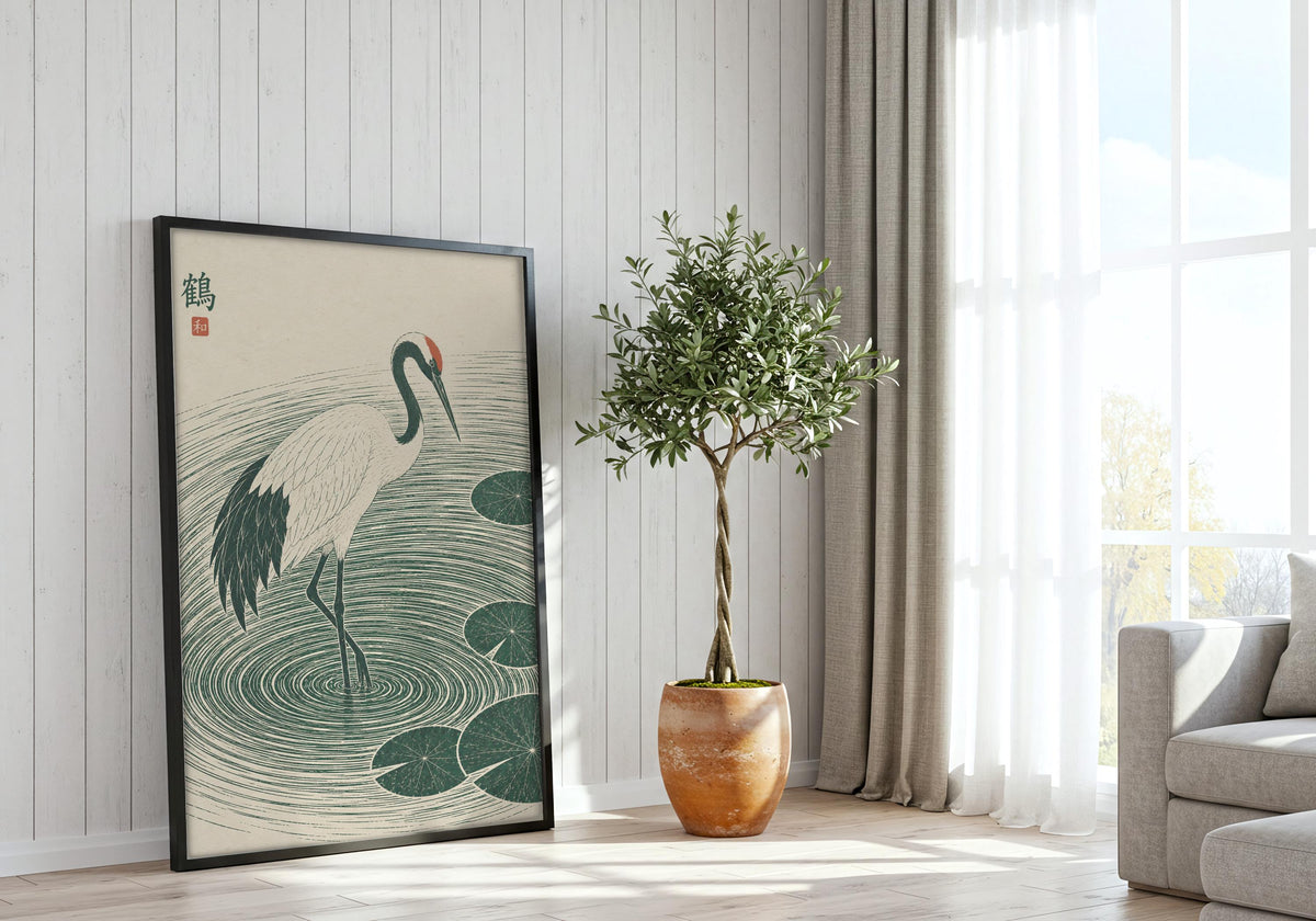 Crane Lily Pond presented as crane wall print, featuring a white crane stepping through deep green ripples and lily pads and hung in a black frame beside a bright window.