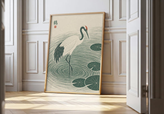 Japanese crane art showing a white crane stepping through deep green ripples and lily pads, leaning in a light natural-wood hero frame against white panelling.