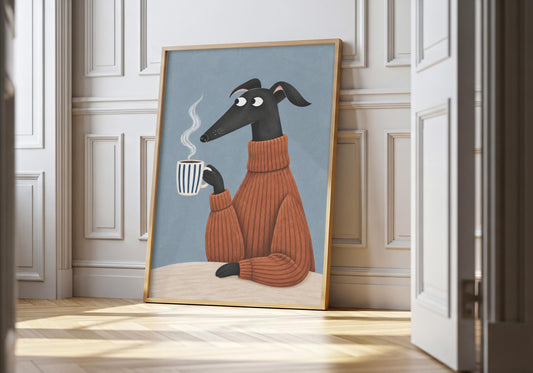 Greyhound print showing a black greyhound in a burnt-orange jumper curled around a striped coffee mug, leaning in a light natural-wood hero frame against white panelling.