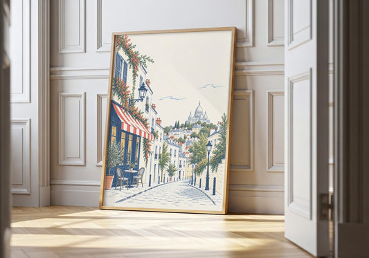 Montmartre print showing a quiet Montmartre street lined with café awnings, trees and pale Parisian buildings, leaning in a light natural-wood hero frame against white panelling.