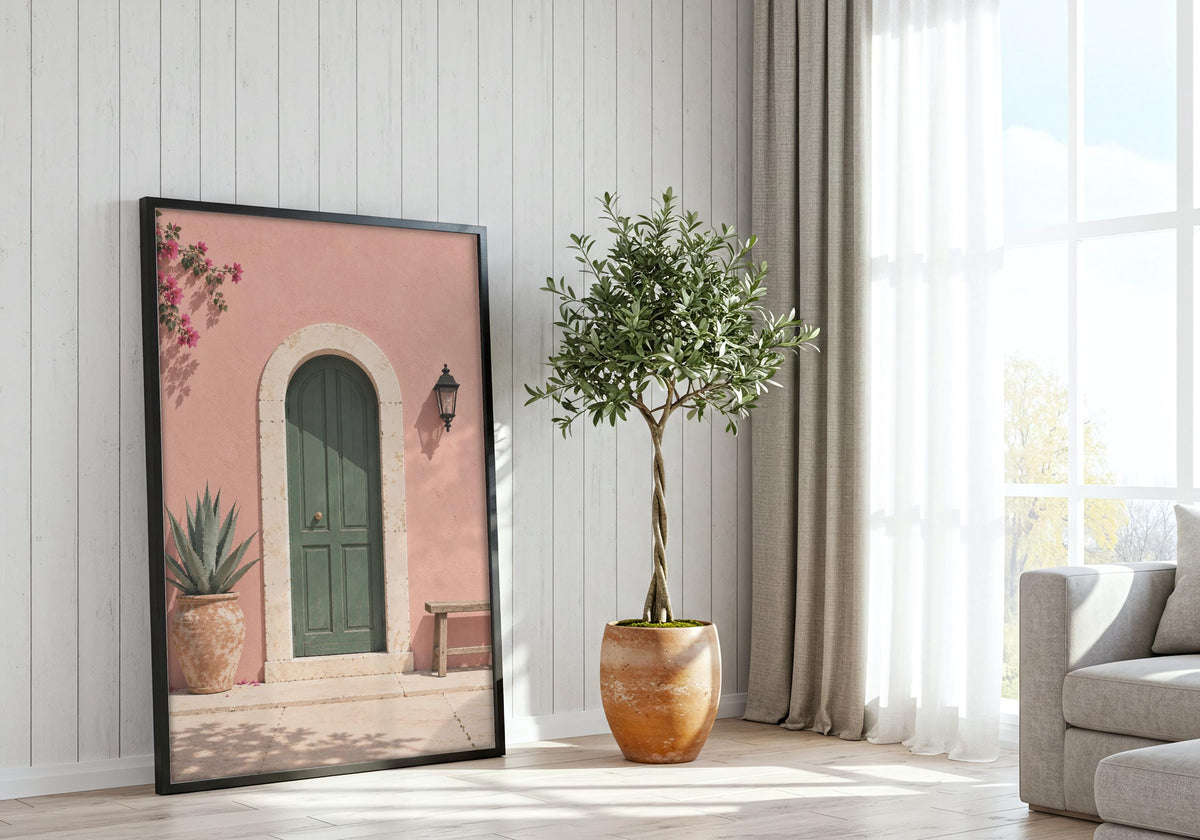 Pink Wall Green Door presented as pink wall art, featuring an arched green door in a blush-pink wall with bougainvillea and a wooden bench and hung in a black frame beside a bright window.