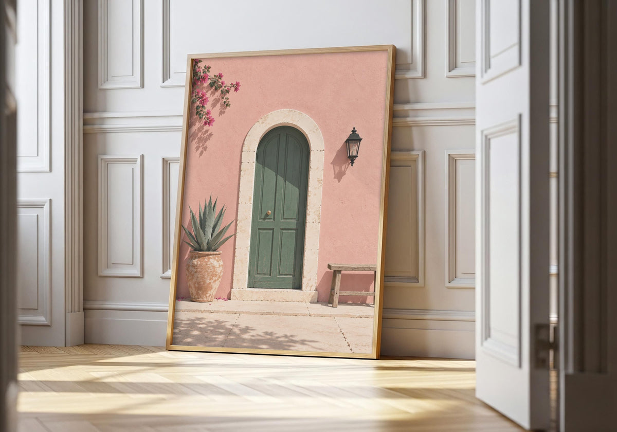 Green door print showing an arched green door in a blush-pink wall with bougainvillea and a wooden bench, leaning in a light natural-wood hero frame against white panelling.