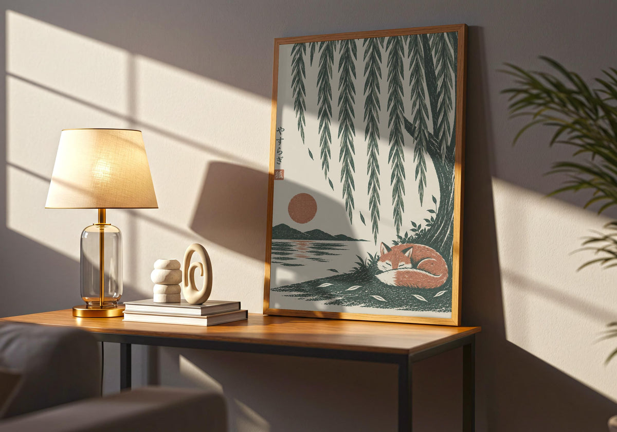 Wide interior view of wabi sabi decor with a rust-coloured fox curled asleep beneath cascading willow branches and a low sun, standing in a dark wood frame on a side table.