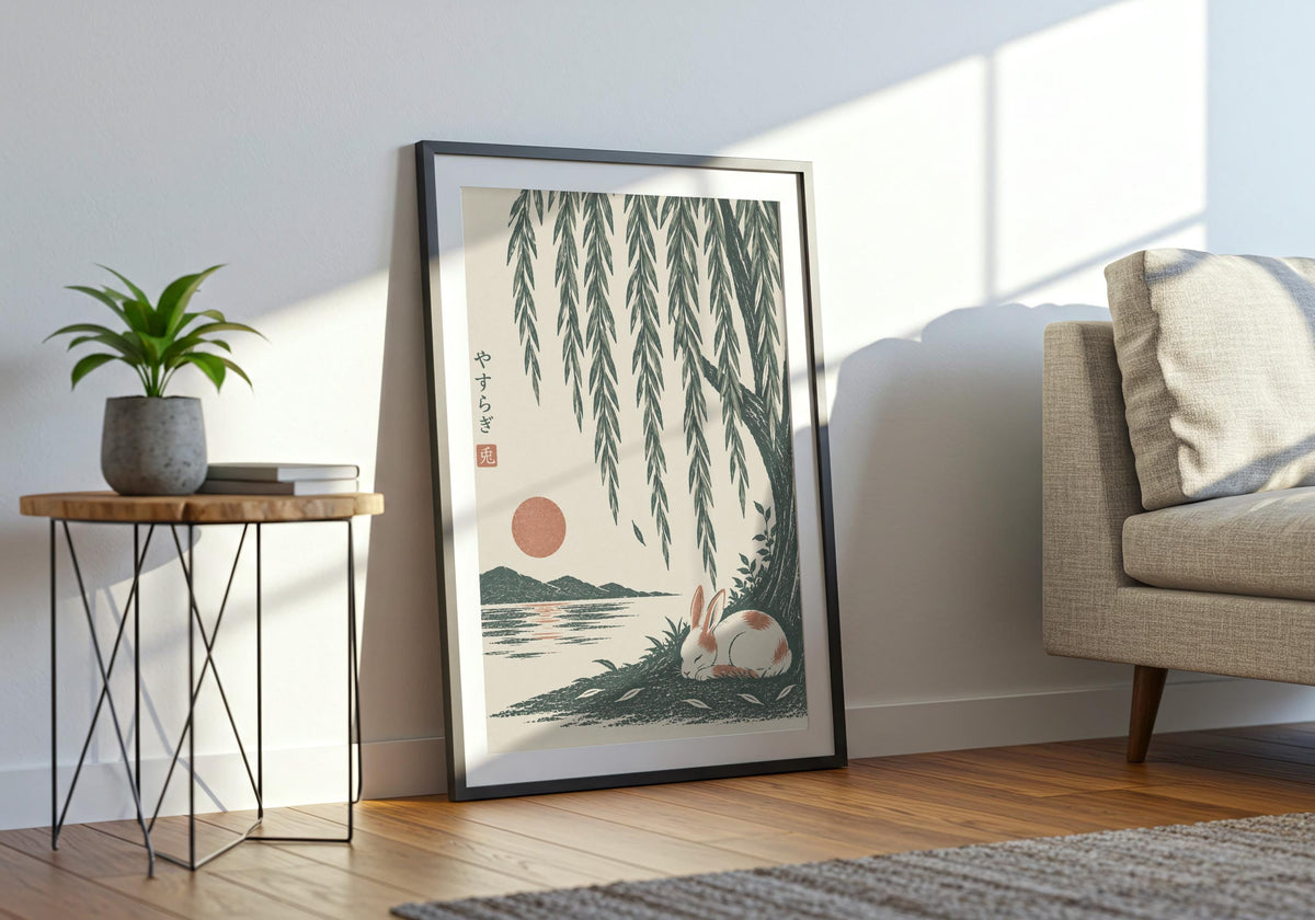 Wide interior view of cottagecore decor with a small white rabbit sleeping beside green water beneath long willow leaves, shown in a black frame beside a pale sofa.