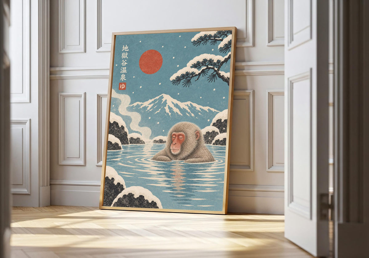 Snow Monkey Onsen snow monkey print in a light wood frame, featuring snow monkeys bathing in a blue hot spring beneath a red sun and snowy mountain.