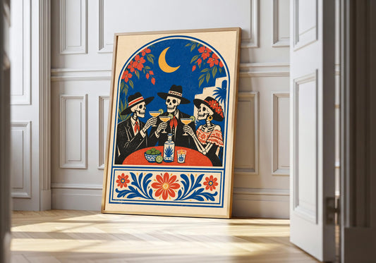 Skeleton tequila toast print showing three skeletons in hats raising margaritas under a crescent moon, leaning in a light natural-wood hero frame against white panelling.