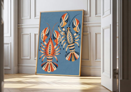 Two patterned lobsters stand out against blue in a coastal folk print leaning inside a light wood frame by white panelling.