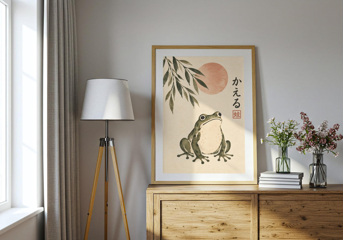 The frog illustration stands on a wooden sideboard beside a lamp, vase and books; dark lettering is visible.