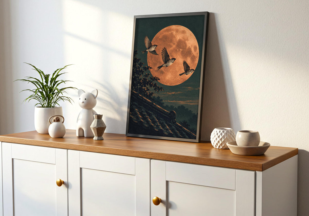 The artwork on a white cabinet with a wooden top includes birds crossing the orange moon.