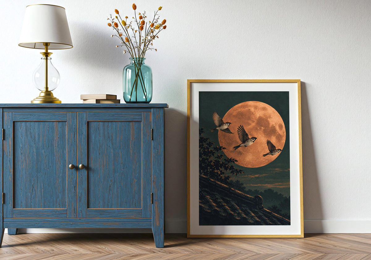 Propped beside a blue cabinet, this framed illustration features fine branch silhouettes.