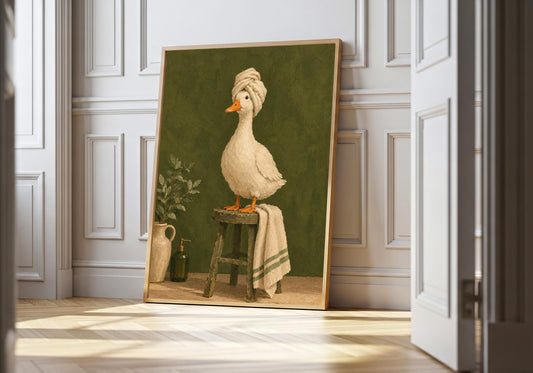 A cream duck with a towel turban stands on a stool in a wood-framed print against white panelling.