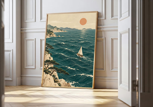 A white sail crosses teal waves in a wood-framed coastal print leaning by white wall panelling.