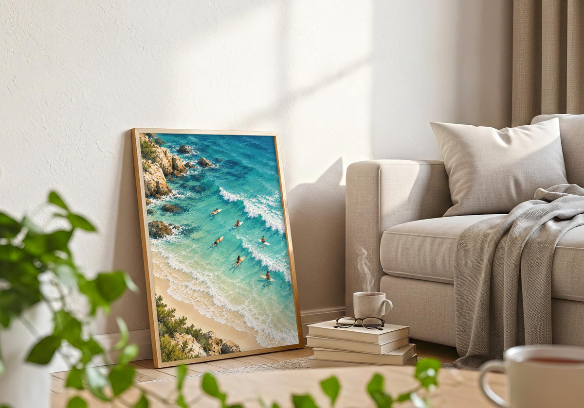 The styling pairs waves approaching the beach with a frame beside a pale sofa, books and foreground greenery.